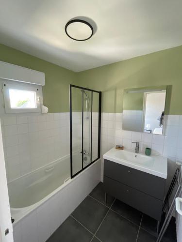 une salle de bain avec une baignoire, un lavabo et une douche dans l'établissement Appartement lumineux vue mer, à Plouhinec