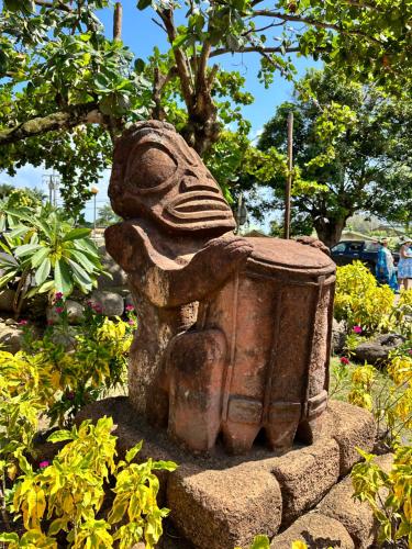 a statue sitting on top of a rock in a garden at Inake Lodge in Atuona