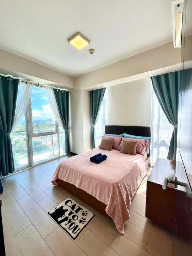 ein Schlafzimmer mit einem Bett mit rosa Bettdecke und großen Fenstern in der Unterkunft SeaBu Properties in Lapu Lapu City