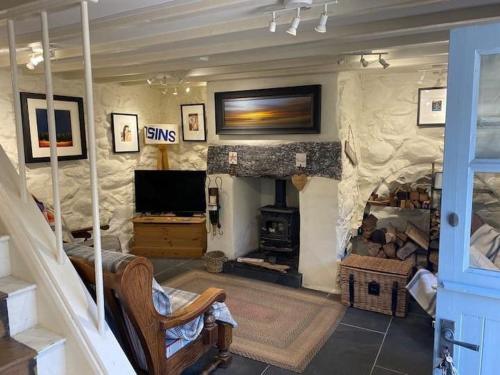 a living room with a stone fireplace and a television at Little Cottage, Llwyngwril in Llwyngwril
