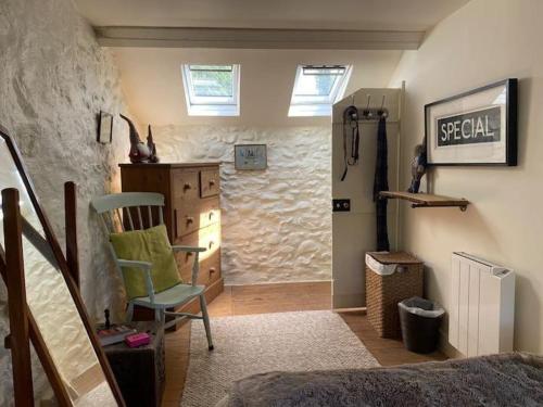 a room with a bed and a chair and a door at Little Cottage, Llwyngwril in Llwyngwril