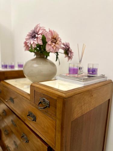 a vase with flowers on top of a wooden cabinet at Casa Iovis in Casagiove