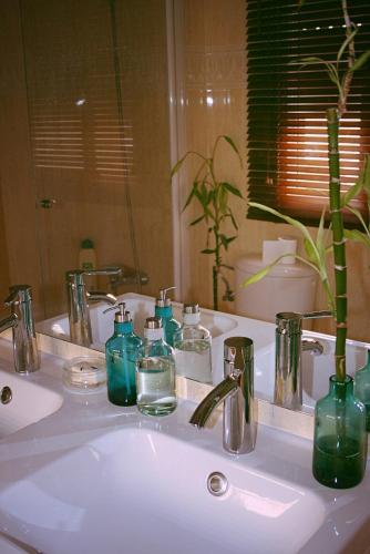 a bathroom sink with green bottles and a mirror at Vive Sanlúcar con aparcamiento en la puerta in Sanlúcar de Barrameda