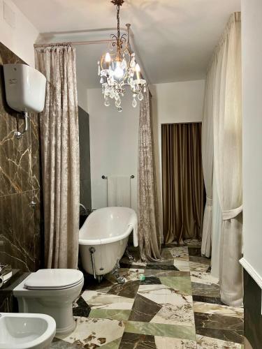 a bathroom with a tub and a toilet and a chandelier at Casa Iovis in Casagiove
