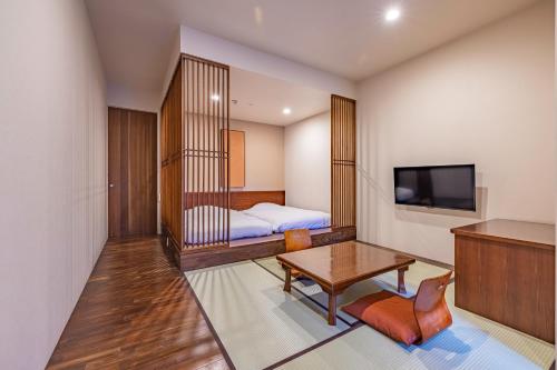 a room with a bed and a table and a tv at Sengokuhara Shinanoki Ichinoyu in Hakone