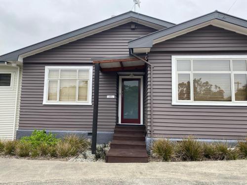 a brown house with a red door and windows at Adventure B&B in Takaka