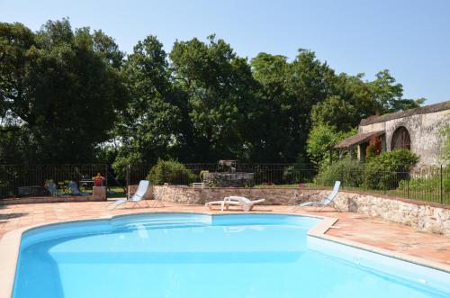 a swimming pool with two chairs and a house at Chambres d'Hôtes du Chateau de Saint Sulpice in La Sauvetat-sur-Lède