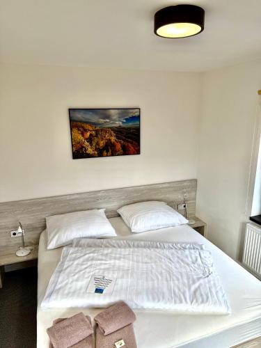 a bedroom with a white bed with a picture on the wall at Resort Mezná in Hřensko