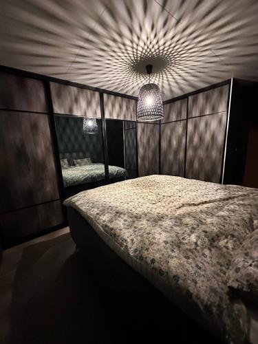 a bedroom with a large bed and a chandelier at Modern apartement with parking in Kvaloysletta