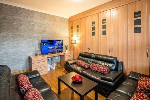 a living room with a leather couch and a tv at Huge 6 Beds House in Zone 2 London-MobileRateOffers-Families-Leisure-Parking-WiFi-PoolTable-Netflix-Sleeps15! in London