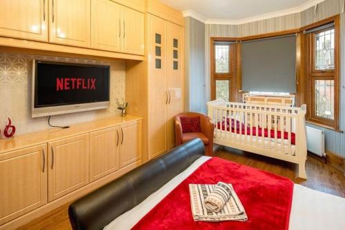 a living room with a television and a crib at Huge 6 Beds House in Zone 2 London-MobileRateOffers-Families-Leisure-Parking-WiFi-PoolTable-Netflix-Sleeps15! in London