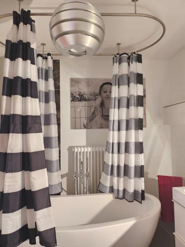 a bathroom with a bath tub with black and white curtains at Ferienwohnung AM HOCHBERG in Bad Kissingen