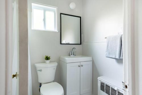 a white bathroom with a toilet and a mirror at Comfortable Brownstown Stay – Queen Bed Private Bath in Woodhaven