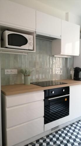 une cuisine avec des armoires blanches et un micro-ondes dans l'établissement Appartement calme et raffiné, à Mâcon
