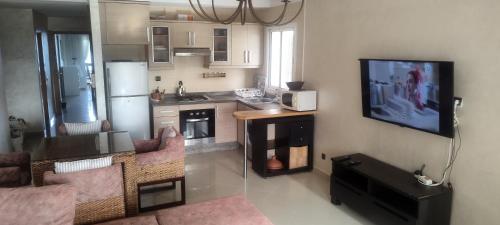 a living room with a kitchen and a tv on a wall at Golf & sea view appartement in Marina golf Asilah in Asilah