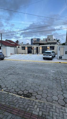 un parcheggio con un'auto parcheggiata di fronte a un edificio di Box 05 a 950 mt do mar, ar- condicionado, TV smart, cozinha privativa a Itapema