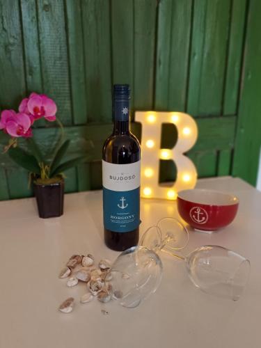 a bottle of wine sitting on a table with glasses at Sailor Apartman Balatonlelle in Balatonlelle