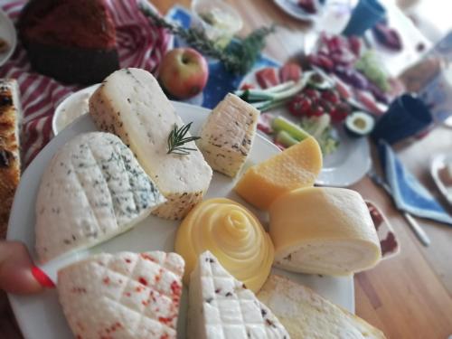 a plate of cheese and fruit on a table at Sailor Apartman Balatonlelle in Balatonlelle