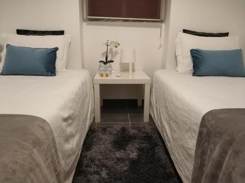 two beds with blue pillows in a room at Sleep & Go Faro Airport Guest House in Faro