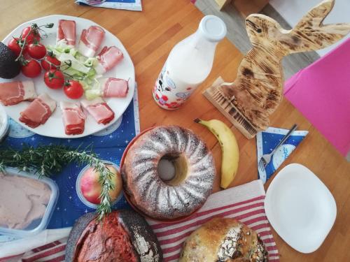 a table with a plate of food with a bagel and fruit at Sailor Apartman Balatonlelle in Balatonlelle