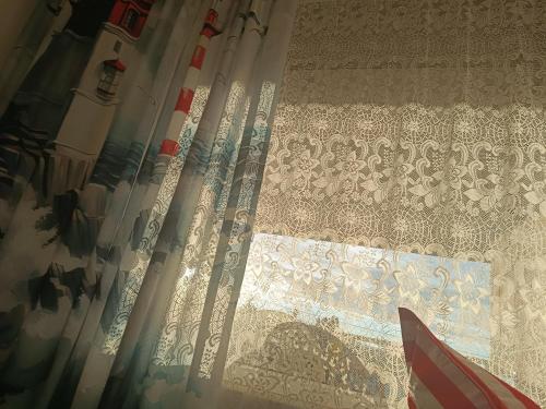a curtain on a window with the light shining through it at Sailor Apartman Balatonlelle in Balatonlelle