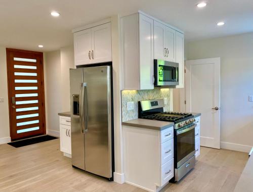 a kitchen with white cabinets and a stainless steel refrigerator at Oasis with pool and music studio by BENVENU in Los Angeles