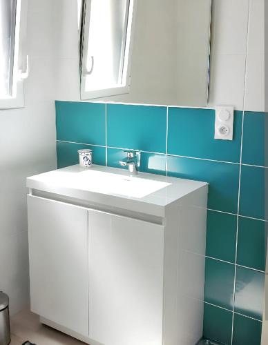 La salle de bains est pourvue d'un lavabo blanc et de carrelage bleu. dans l'établissement Villa charmante avec piscine privée à Saint-Jean-de-Monts, à Saint-Jean-de-Monts