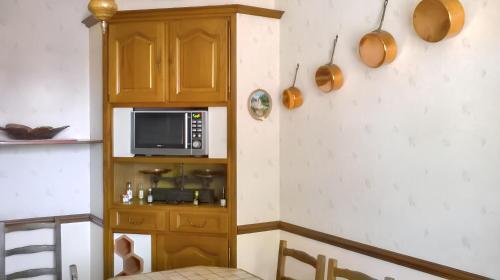 La cuisine est équipée d'un four micro-ondes et d'une armoire en bois. dans l'établissement Maison confortable à Le Mans avec jardin et terrasse, au Mans