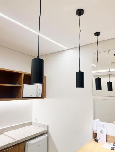 a kitchen with three black lights hanging from the ceiling at Apto Premium Resort in Salinópolis