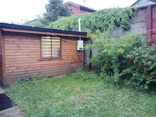 a small house with a yard next to a building at Cabaña interior en barrio residencial in Puerto Montt