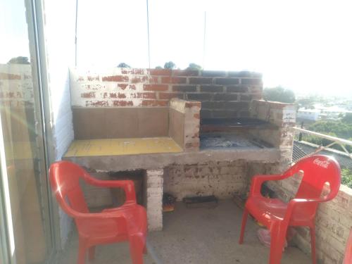 two red chairs sitting in front of a brick oven at Cabañas Mirador de Soledad in El Quisco