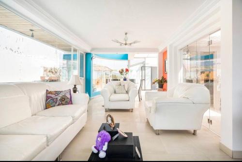 a living room with white furniture and a teddy bear on a table at Suite Lili in Quito