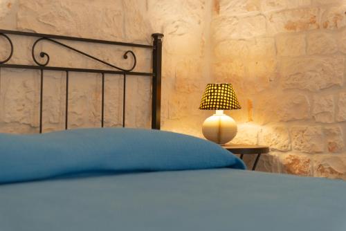 a bed with a blue pillow and a lamp at Trulli Mirabilis in Cisternino