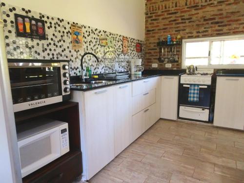 a kitchen with white cabinets and a brick wall at Casa Quinta Tambo in Garupá