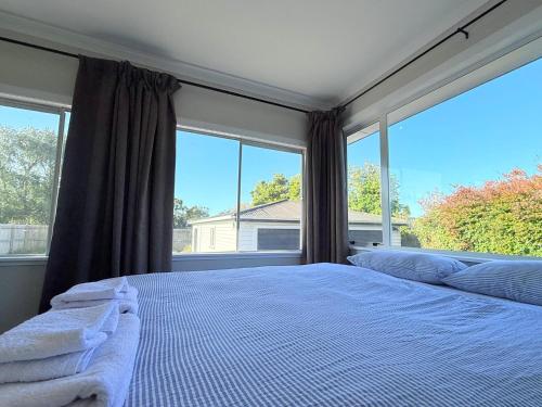 a bedroom with a large bed with a large window at Cozy Taranaki Homestay in Stratford