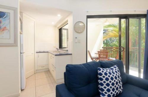 a living room with a blue couch and a kitchen at Charming 1 bedroom Apt - Close to Town & Beach in Port Douglas