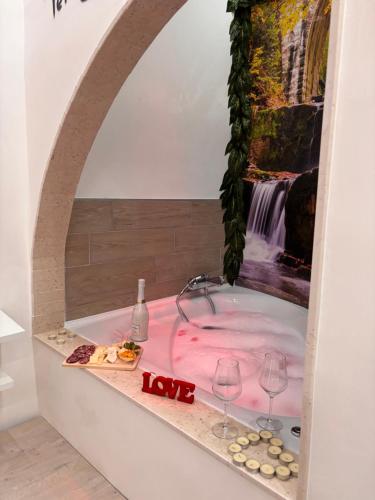 una vasca da bagno con bicchieri da vino e un dipinto di una cascata di La dolce sosta ad Acerra