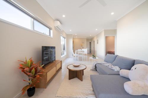 a living room with a blue couch and a tv at Bottlebrush Retreat - 4BR Home in Griffin in Griffin