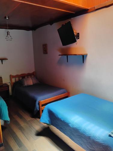 a room with two beds and a flat screen tv at Alta Frontera Hostal in Los Ángeles