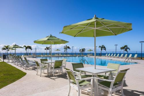 a table and chairs with umbrellas next to a pool at Holiday Inn Ponce & El Tropical Casino by IHG in Ponce