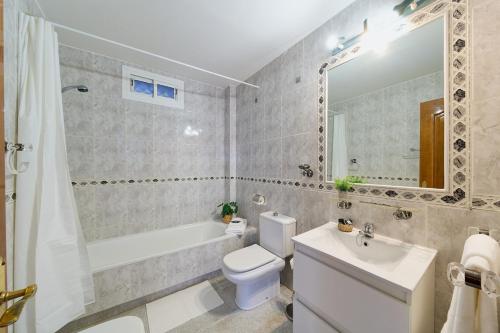 a bathroom with a white toilet and a tub and a sink at ROSE I Vistas and direct access to the sea Mijas Costa in Málaga
