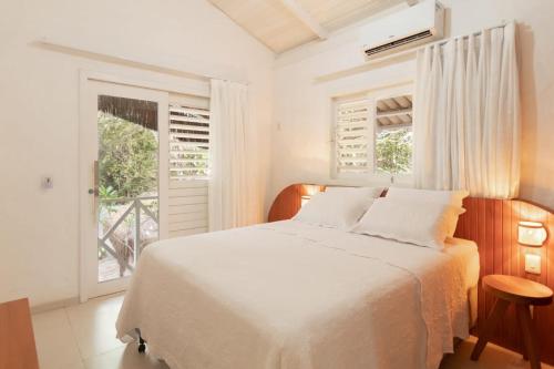 Un dormitorio blanco con una cama y una ventana. en primeira vista pipa, en Pipa