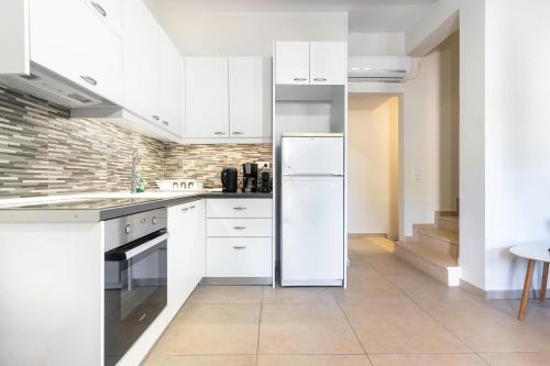 a kitchen with white cabinets and a white refrigerator at Vina's Stone House in Limeni