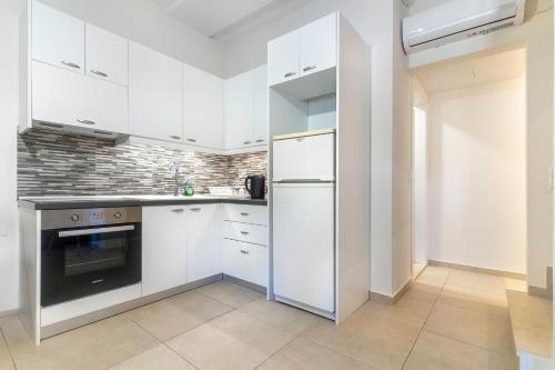a kitchen with white cabinets and a refrigerator at Vina's Stone House in Limeni