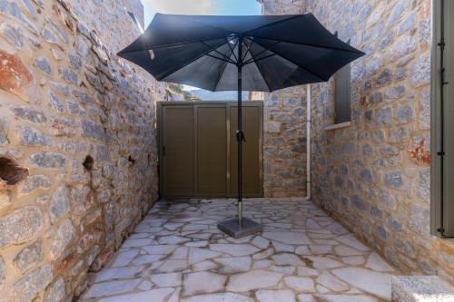 an umbrella sitting on a stone walkway next to a door at Vina's Stone House in Limeni