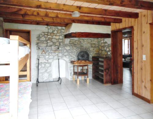 Cette chambre est dotée d'un mur en pierre, d'un bureau et d'une table. dans l'établissement Maison isolée et calme à Septmoncel avec vue sur montagne, à Septmoncel