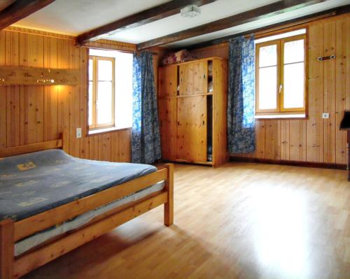 a bedroom with a bed with wooden walls and windows at Maison isolée et calme à Septmoncel avec vue sur montagne in Septmoncel