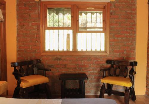 two chairs in front of a brick wall with a window at Rancho San Antonio in Salento