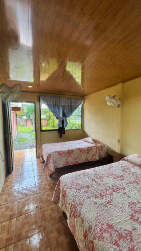 a hotel room with three beds and two windows at Cabinas Caño Negro in Los Chiles