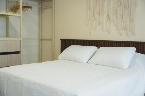 a white bed with two pillows on top of it at Casa Serena in Ibagué